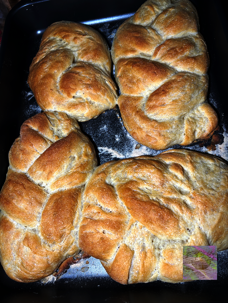 Freshly baked braided bread on a baking tray, showing a golden-brown crust.