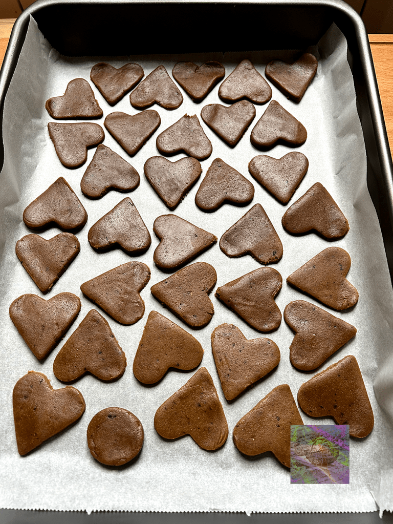 En plåt med pepparkaksdeg i form av hjärtan och en rund form, redo för gräddning.